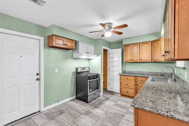 kitchen featuring ceiling fan, sink, light stone countertops, and gas stove