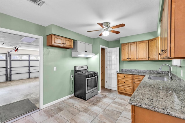 kitchen featuring gas stove, light stone countertops, sink, and ceiling fan