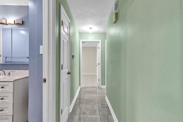 hallway featuring sink and a textured ceiling