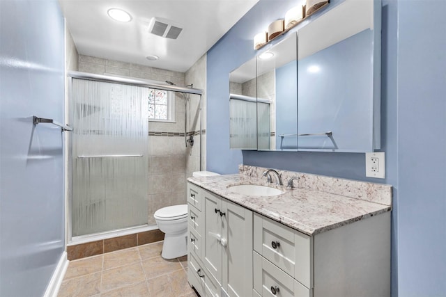 bathroom featuring vanity, toilet, and a shower with shower door