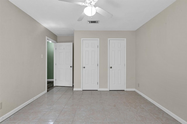 unfurnished bedroom featuring multiple closets, ceiling fan, and light tile patterned floors