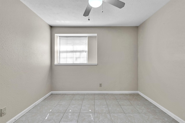 unfurnished room with ceiling fan, light tile patterned floors, and a textured ceiling