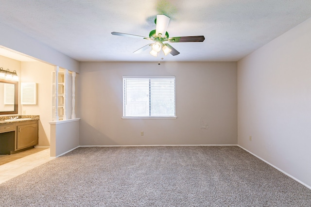 carpeted empty room with ceiling fan, sink, and a textured ceiling