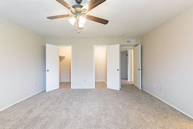 unfurnished bedroom featuring ceiling fan, a spacious closet, a closet, and light carpet