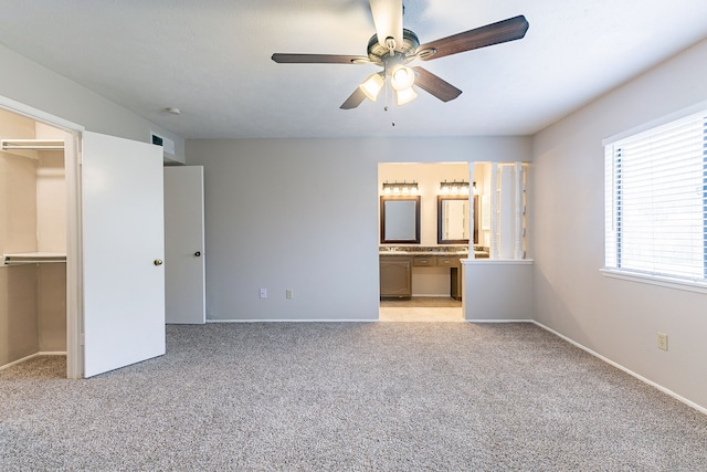 unfurnished bedroom featuring ensuite bathroom, a spacious closet, light carpet, a closet, and ceiling fan