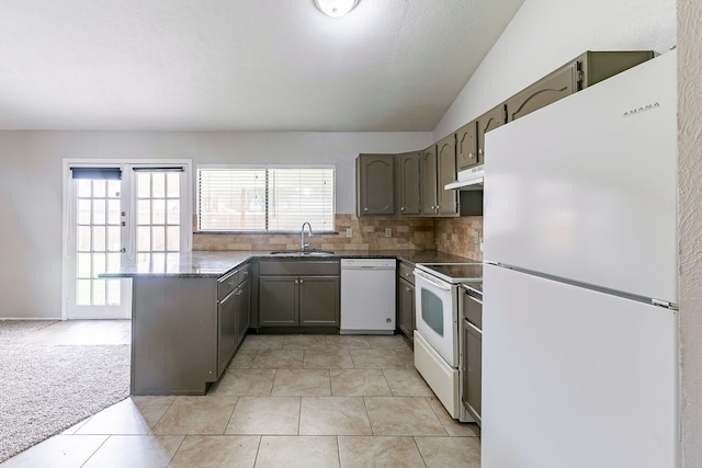 kitchen featuring lofted ceiling, sink, decorative backsplash, kitchen peninsula, and white appliances