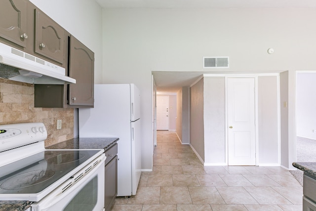 kitchen featuring backsplash, a towering ceiling, light tile patterned flooring, and white range with electric cooktop