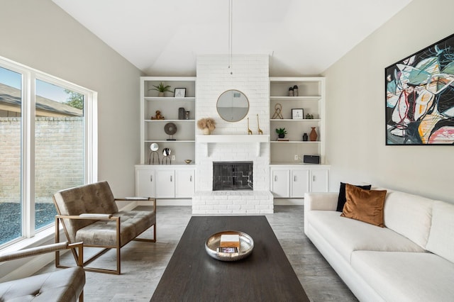 living room with a fireplace, dark wood-type flooring, vaulted ceiling, and a healthy amount of sunlight