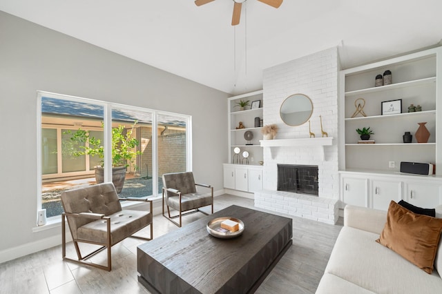 living room featuring ceiling fan, high vaulted ceiling, a fireplace, light hardwood / wood-style floors, and built in shelves