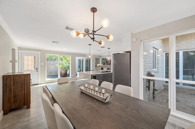 dining area featuring an inviting chandelier, ornamental molding, and light hardwood / wood-style floors