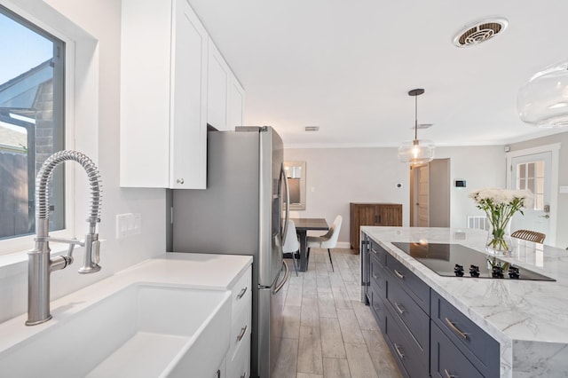 kitchen with sink, decorative light fixtures, black electric cooktop, light hardwood / wood-style floors, and white cabinets