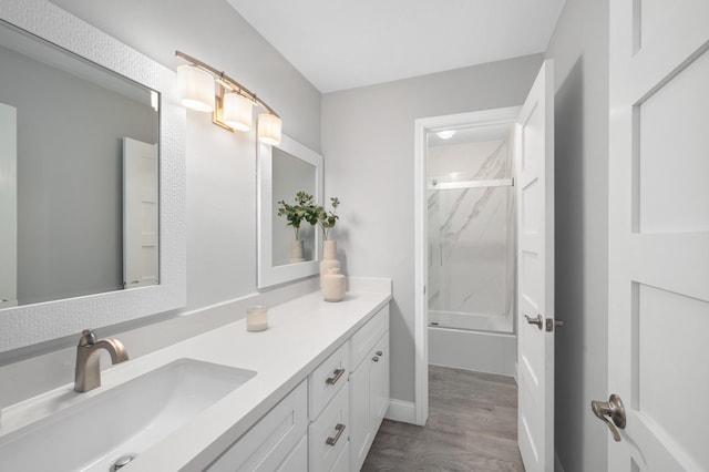 bathroom featuring enclosed tub / shower combo, vanity, and wood-type flooring