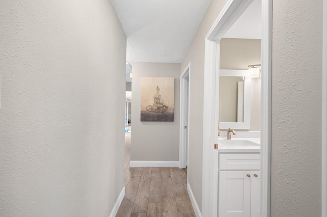 hallway with sink and light hardwood / wood-style floors