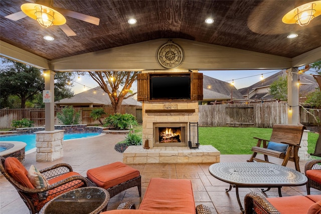 view of patio featuring ceiling fan, an outdoor stone fireplace, a fenced backyard, and a fenced in pool