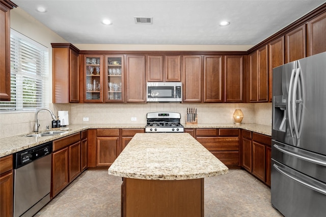 kitchen featuring visible vents, a kitchen island, appliances with stainless steel finishes, a sink, and backsplash