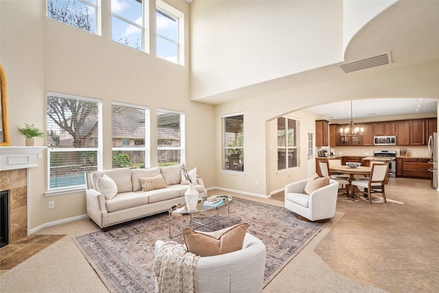 living room featuring a healthy amount of sunlight, visible vents, arched walkways, and a tiled fireplace