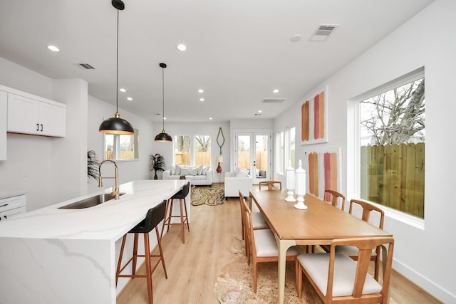 dining area with sink, light wood-type flooring, and french doors