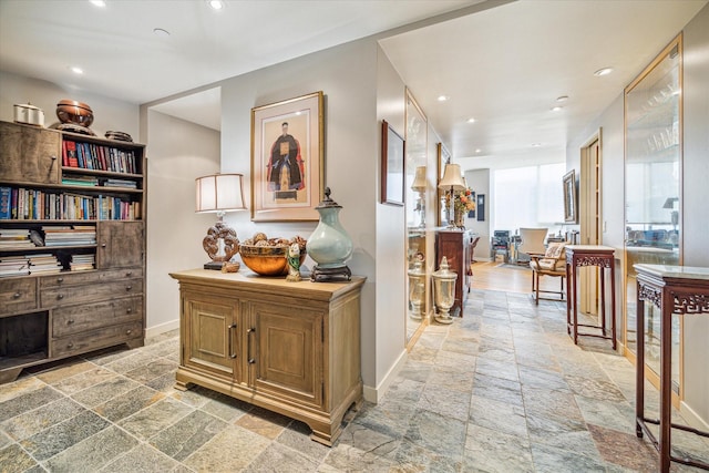 corridor with recessed lighting, baseboards, and stone tile flooring