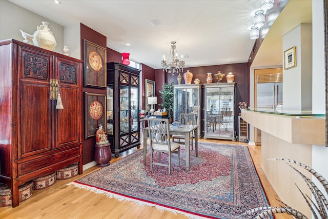 dining area with light hardwood / wood-style floors and a chandelier