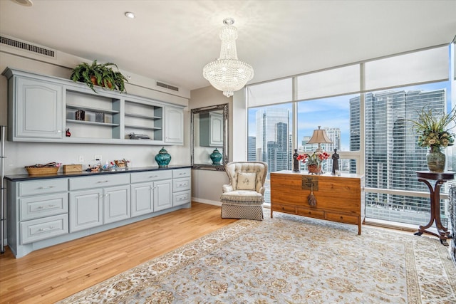 living area with a notable chandelier, a wealth of natural light, and light wood-type flooring