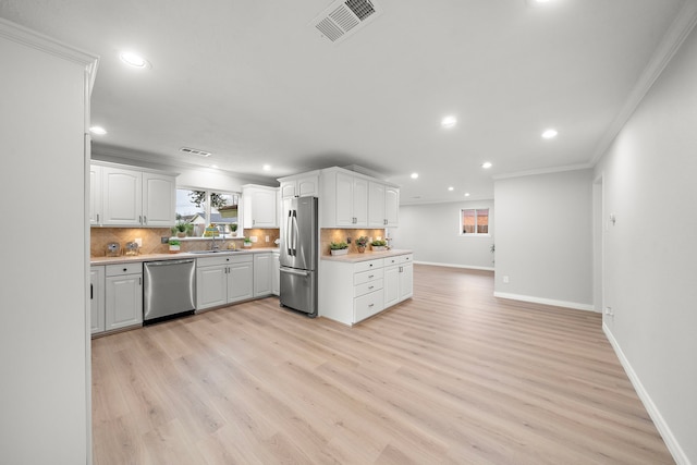 kitchen with white cabinetry, appliances with stainless steel finishes, crown molding, and decorative backsplash