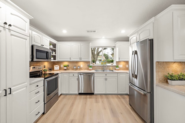 kitchen featuring stainless steel appliances, sink, light hardwood / wood-style flooring, and white cabinets