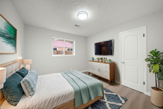 bedroom with light hardwood / wood-style flooring and a textured ceiling