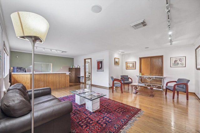 living room featuring crown molding, rail lighting, and light hardwood / wood-style floors