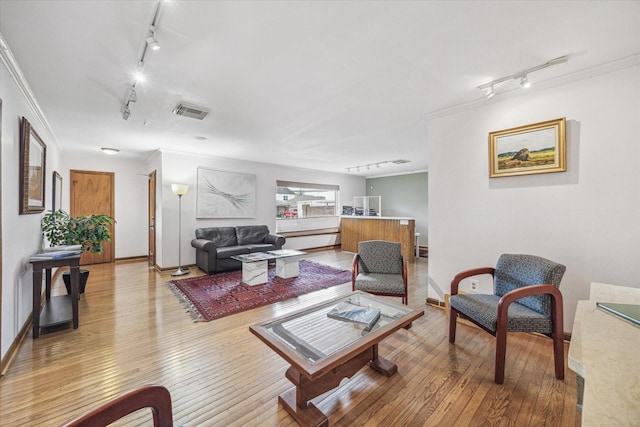 living room with ornamental molding, rail lighting, and hardwood / wood-style floors