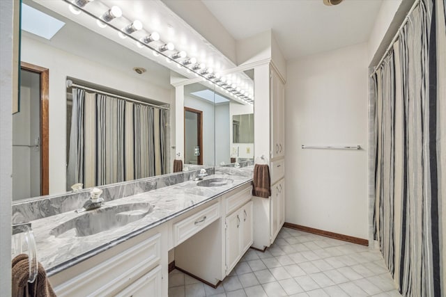 bathroom with tile patterned flooring, vanity, and a skylight