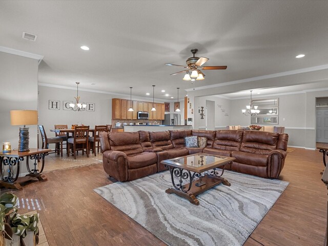 living room with recessed lighting, ornamental molding, ceiling fan with notable chandelier, visible vents, and wood finished floors