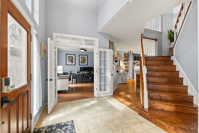 entryway featuring ceiling fan, a high ceiling, french doors, stairway, and stone tile flooring