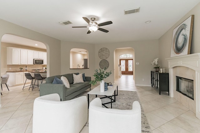 tiled living room with french doors and ceiling fan