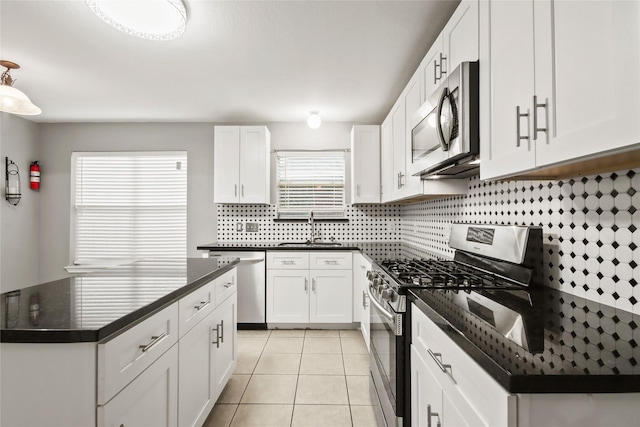 kitchen with stainless steel appliances, white cabinetry, a center island, and sink