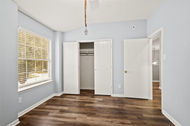 unfurnished bedroom featuring dark wood-type flooring, a closet, and vaulted ceiling