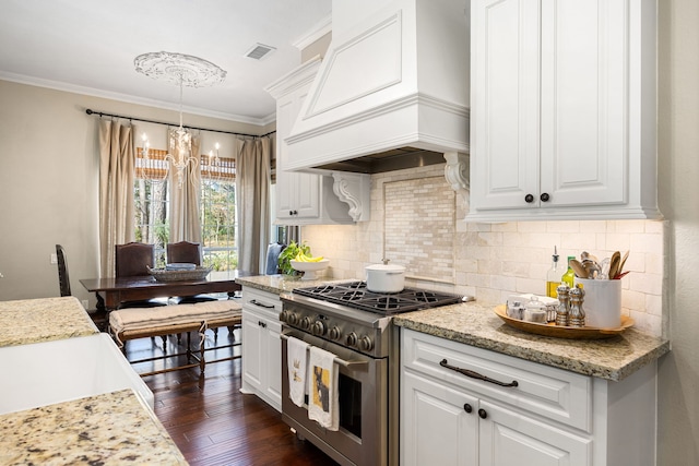 kitchen featuring stainless steel stove, premium range hood, hanging light fixtures, light stone counters, and white cabinets