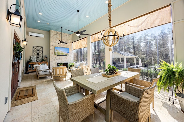 sunroom with an outdoor stone fireplace, ceiling fan with notable chandelier, and an AC wall unit