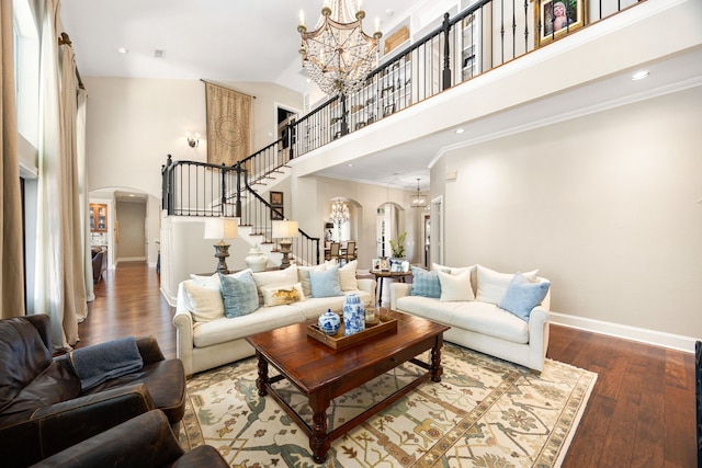 living room with a high ceiling, ornamental molding, wood-type flooring, and a chandelier