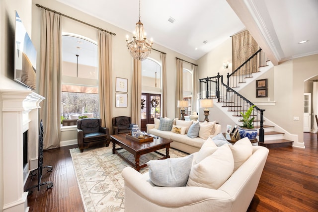 living room with a chandelier, a high ceiling, crown molding, dark wood-type flooring, and french doors