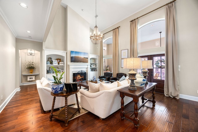 living room with an inviting chandelier, dark hardwood / wood-style floors, built in features, and a high ceiling