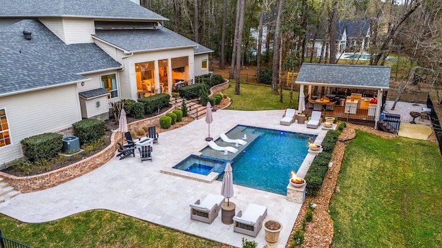 view of pool with a bar, a patio area, a lawn, and an in ground hot tub