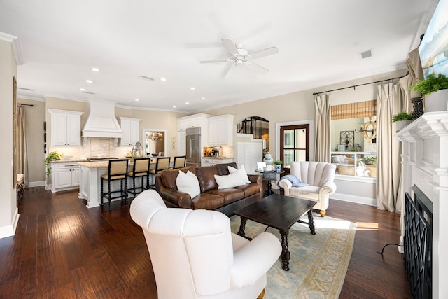 living room with ornamental molding, dark wood-type flooring, and ceiling fan