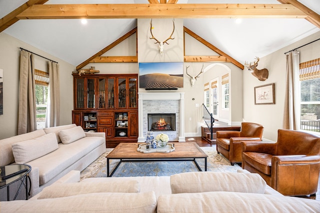 living room with high vaulted ceiling, a fireplace, light hardwood / wood-style floors, and beamed ceiling