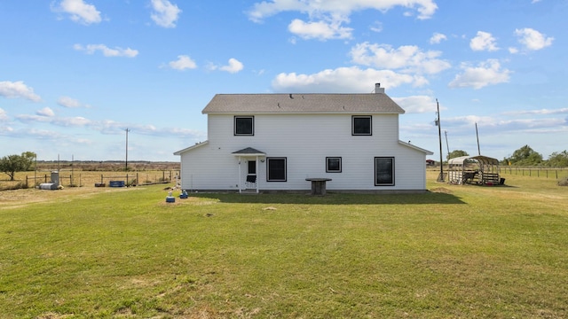 rear view of house with a rural view and a lawn