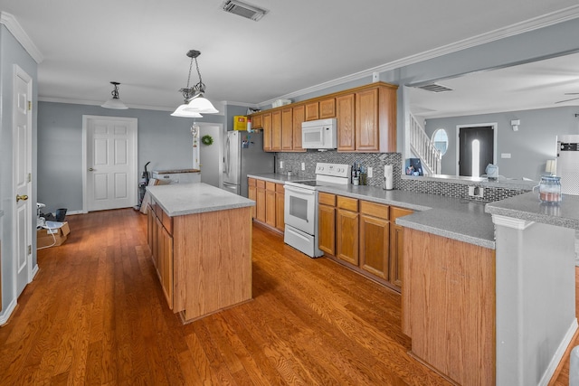 kitchen with crown molding, tasteful backsplash, wood-type flooring, a center island, and white appliances