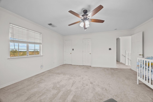 unfurnished bedroom with ornamental molding, light carpet, and ceiling fan