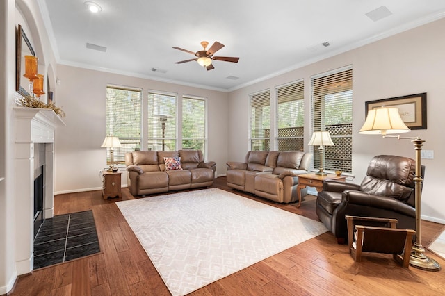 living room featuring hardwood / wood-style floors, crown molding, and a tile fireplace