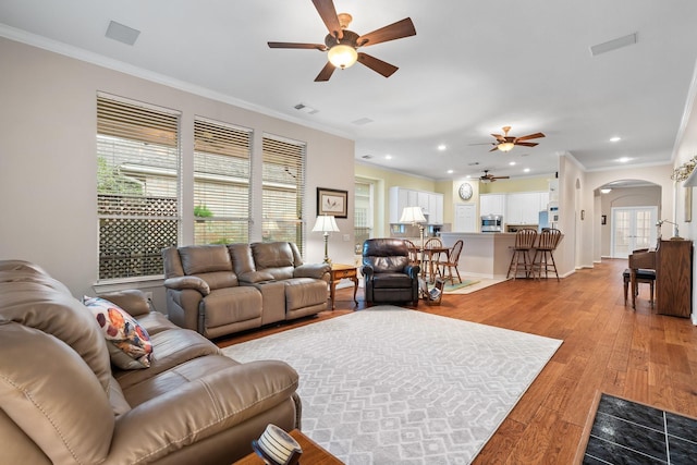 living room with light hardwood / wood-style flooring, ornamental molding, and ceiling fan