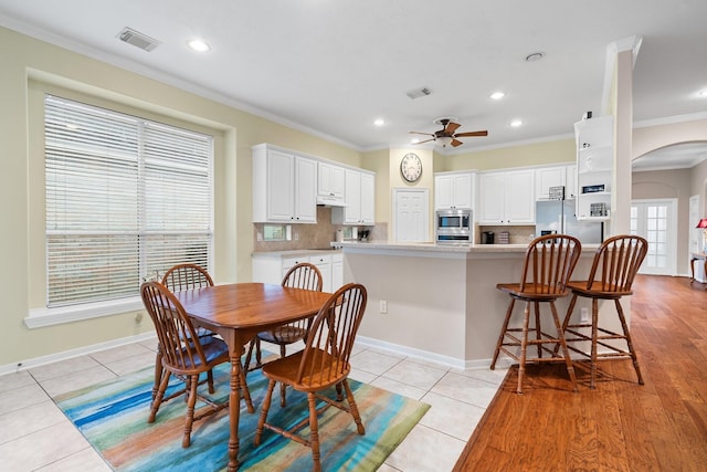 tiled dining area with crown molding and ceiling fan