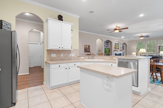 kitchen featuring white cabinetry, stainless steel appliances, kitchen peninsula, and a kitchen island